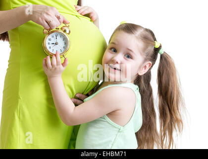 Kind schaut Wecker und schwangeren Bauch Stockfoto