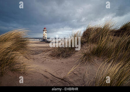 Foto von einem Leuchtturm an einem stürmischen Tag zwischen Sanddünen umrahmt. Stockfoto