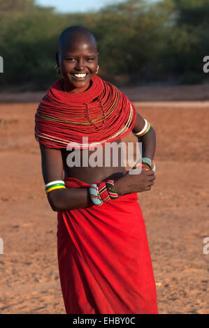 Lächelndes Samburu-Mädchen mit riesigen roten ockerfarbenen Perlenketten und einem roten Tuch um ihre Taille, Archer's Post Area, Kenia Stockfoto