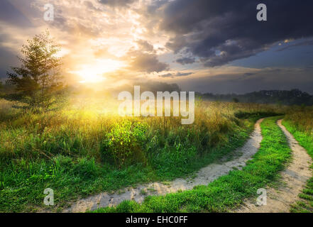 Sonne und graue Wolken über Landstraße Stockfoto