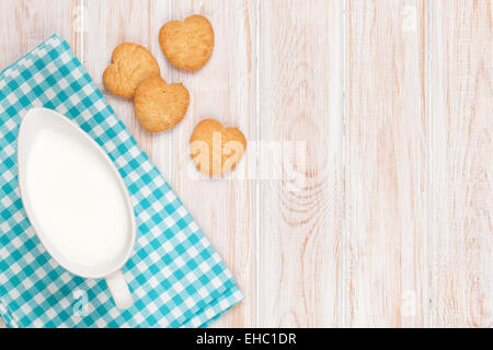Krug mit Milch und Herz geformt Cookies auf weißer Holztisch mit Textfreiraum Stockfoto