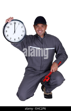 Klempner hält eine Uhr Stockfoto