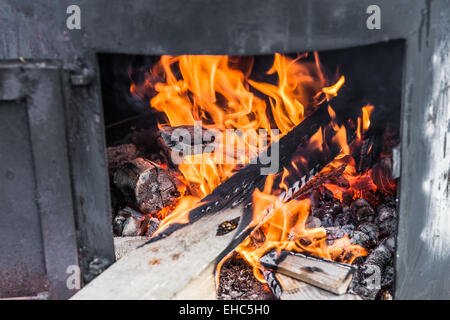 Feuer brennt in der Outdoor-Ofen aus Metall. Feuerholz in den Ofen Stockfoto