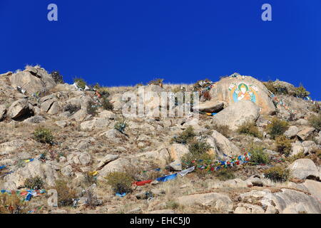 Tibetische buddhistische Gebetsfahnen und Malerei auf Mani Stein - Om Mani Padme Hum-. Heap Kloster Drepung-Reis Gelugpa-gelben Hut. Stockfoto