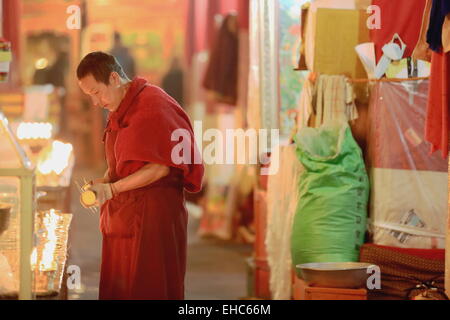 DREPUNG, TIBET, CHINA-Oktober 19: Tibetisch-buddhistischen Mönch Lichter Kerzen in der Sutra-Halle der Coqen Hall in der 19. Oktober 2012 Stockfoto