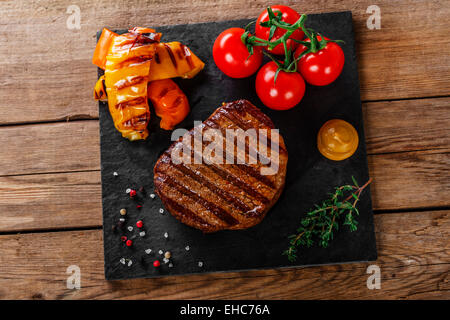 Gegrilltes Rindersteak mit Gemüse auf einer Holzoberfläche Stockfoto