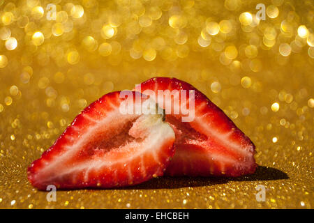 Offenen Erdbeere auf gold glitzernden Hintergrund voller Bokeh. Stockfoto