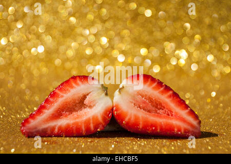 Offenen Erdbeere auf gold glitzernden Hintergrund voller Bokeh. Stockfoto