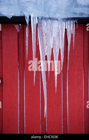 Eiszapfen hängen von Dach Stockfoto