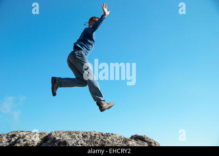 Mann springt auf den Felsen mit Landschaft Hintergrund Stockfoto