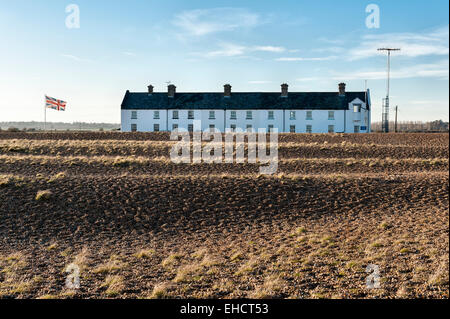 Eine Reihe alter Cottages der Küstenwache im abgelegenen Dorf Shingle Street, Suffolk, an der britischen Ostküste. Ein Kommunikationsturm befindet sich auf der rechten Seite Stockfoto