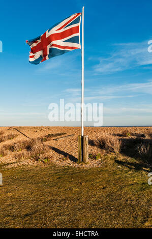 Die Flagge der Union Jack, die über dem abgelegenen und einsamen Küstenort Shingle Street in Suffolk, Großbritannien, in der Nähe von Aldeburgh an der britischen Ostküste fliegt Stockfoto