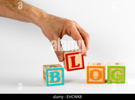 Männliche Hand Rechtschreibung das Wort Blog mit bunte Kinder-Blöcken auf weißem Hintergrund Stockfoto