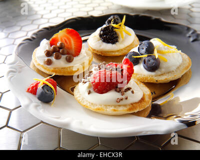 Süße blinis Canipe, Blini gekrönt mit Creme fraiche, Erdbeer und Schokolade und frischen Blaubeeren Stockfoto