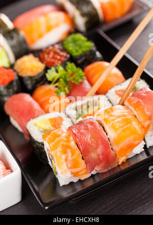 Auf schwarzen Teller und Stein serviert köstliche Sushi-Rollen Stockfoto