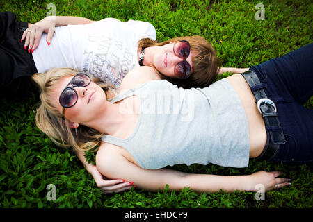 Zwei Mädchen in Sonnenbrille lag auf dem grünen Rasen Stockfoto