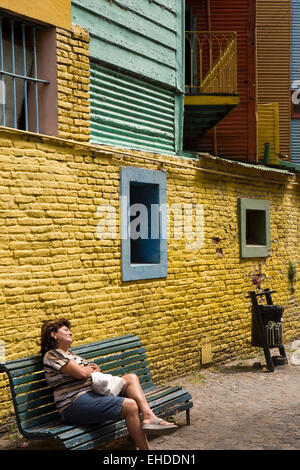 Argentinien, Buenos Aires, La Boca, Caminito, Frau ruht auf Bank unter bunt bemalten Häuser Stockfoto