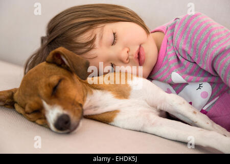 Kleinkind Mädchen schläft neben Mischling Welpe Hund
