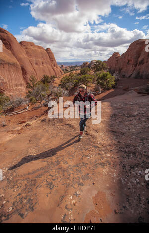 offene breite Porträt einer jungen Frau in Aktion Rucksackreisen durch die Wüste in arches Nationalpark Moab utah Stockfoto