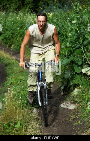 Mountainbiker auf alte Landstraße im Wald Stockfoto