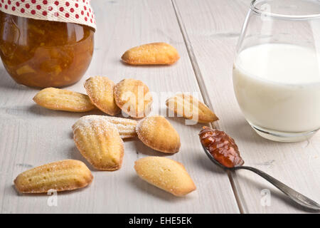 Französische Orangenblütenwasser parfümiert Kekse - Madeleines, Orangenmarmelade und Glas Milch Stockfoto