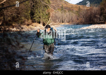 Backpacker Wade robusten Fluss Stockfoto