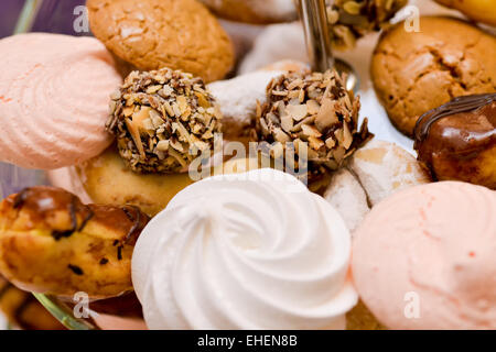 Kekse, Marshmallows, Eclair, Schokokugeln mit Nüssen auf Glasauflage gelegt Stockfoto