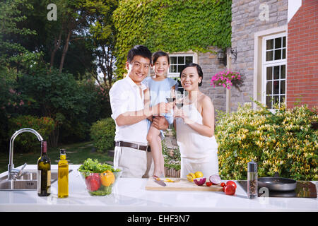 Eltern halten einen Rotwein und Tochter außerhalb der Küche Stockfoto