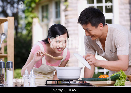 Das junge Paar, die Suppe in der Küche zu probieren Stockfoto