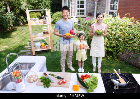 Eine Familie mit drei mit Gemüse in der Outdoor-Küche Stockfoto