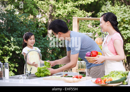 Eine glückliche Familie von drei in der Outdoor-Küche Gemüse putzen Stockfoto