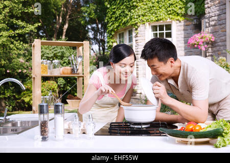 Das junge Paar, die Suppe in der Küche zu probieren Stockfoto