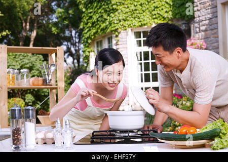 Das junge Paar, die Suppe in der Küche zu probieren Stockfoto