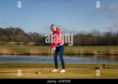 Frau von auf einen Golfplatz stehen in der Tee-Box vor ein Wasserhindernis mit einem Fahrer in ihren Händen bereit zum Abschlag Abschlag Stockfoto