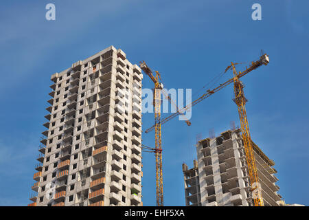 Zwei Kräne entwickelnden Wohngebäude gegen blauen Himmel Stockfoto