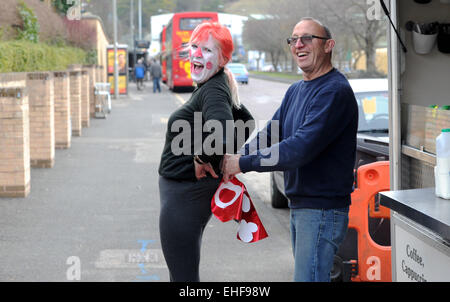 Brighton, UK. 13. März 2015. Kunden Martin Williamson hilft mobilen Café-Besitzer Kim Coghlan mit ihrem Comic Relief Red Nose-Outfit in Brighton Vormittag Credit: Simon Dack/Alamy Live News Stockfoto
