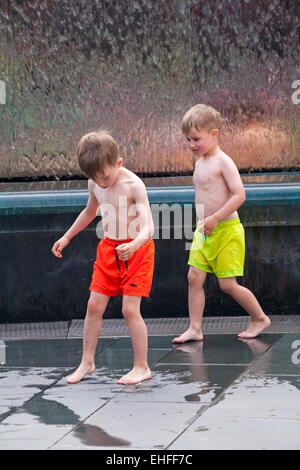 genießen das Wasser - Kinder spielen im Wasserbrunnen im Millenium Square, Harbourside, Bristol im Mai Stockfoto