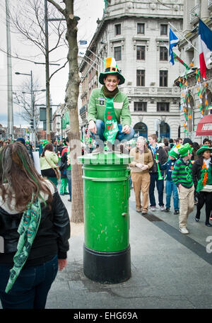 Touristischen Mann gekleidet in grün mit Kobold Hut sitzt auf grünen Briefkasten in O Connell Street, Dublin, Irland, am St. Patricks Day Stockfoto