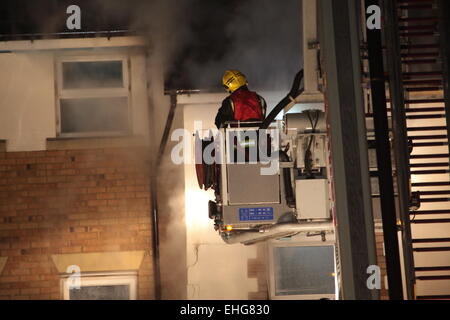 London, UK. 13. März 2015. Zehn Feuerwehrautos aus East London in Angriff genommen einen Brand in einem Wohnblock in bellen am frühen Morgen. Londoner Feuerwehr berichtet, dass das Feuer Teil der dritten Etage des Blocks betraf, und einige Stunden später berichtete, dass Teile des Daches und der Wände entfernt, Zugang und bekämpfen den Brand gekürzt wurden. Es versteht sich, dass alle Bewohner in der Lage waren, das Gebäude zu verlassen, die, das Vereinten Nationen geschädigt, und es keine gemeldeten Verluste gibt. Auf den Vorfall reagiert auch London Ambulance Service explosionsgefährdeten Bereich Response Team. Stockfoto