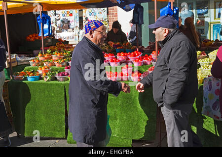 Zwei Männer treffen vor Obst stall bei St Albans Markt, St Peters Street, St Albans, Hertfordshire, England, UK Stockfoto