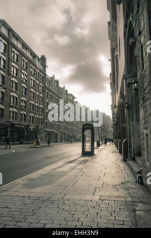 Telefonbox an der leeren Charing Cross Road, London. Schwarz-Weiß-Bild neblig Sonntagmorgen im November 2014 Stockfoto