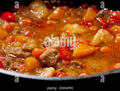 Fleisch und Gemüse Eintopf kochen in einem schwarzen Gusseisen Topf Stockfoto