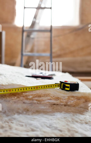 Maßband und Messer auf Mineralwolle, Nahaufnahme Stockfoto