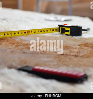 Maßband und Messer auf Mineralwolle, Nahaufnahme Stockfoto