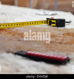 Maßband und Messer auf Mineralwolle, Nahaufnahme Stockfoto