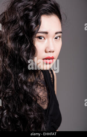 Portrait von schöne Mode Modell mit langen Haaren über grauer Hintergrund posiert. Stockfoto