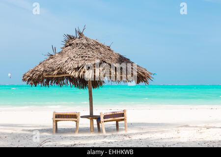 Zwei Liegestühle und Sonnenschirm am tropischen Strand. Stockfoto