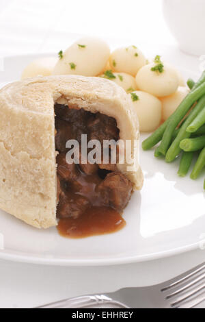 Steak und Niere Pudding serviert eine traditionelle gedämpfte Talg Konditorei Torte mit neuen Kartoffeln und grünen Bohnen Stockfoto