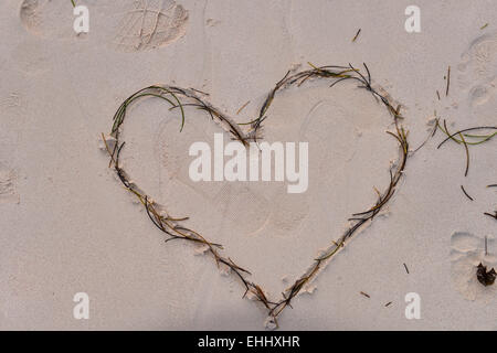 Herz durchbohrt von Amors Pfeil in den Sand gezeichnet Stockfoto
