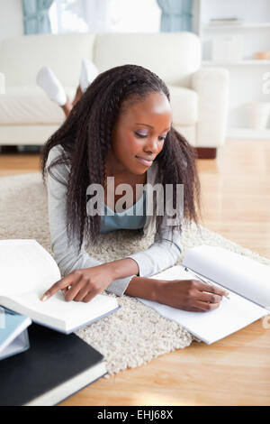 Frau liegend auf Teppich ihre Hausaufgaben Stockfoto